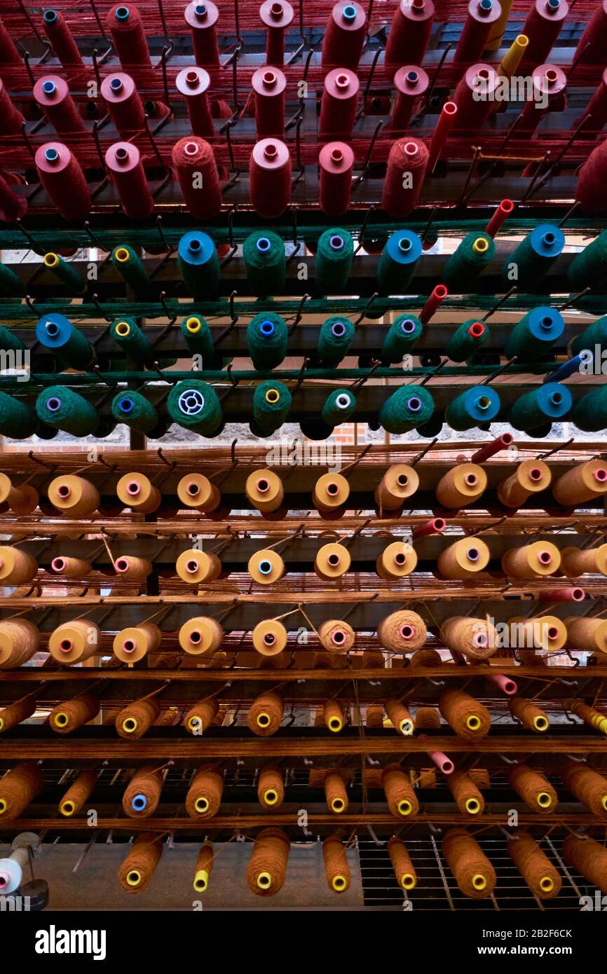 Fadenreihen auf Spulen sind bereit, einen Webstuhl zu liefern. Im National Wool Museum in Geelong, Victoria, Australien. Stockfoto