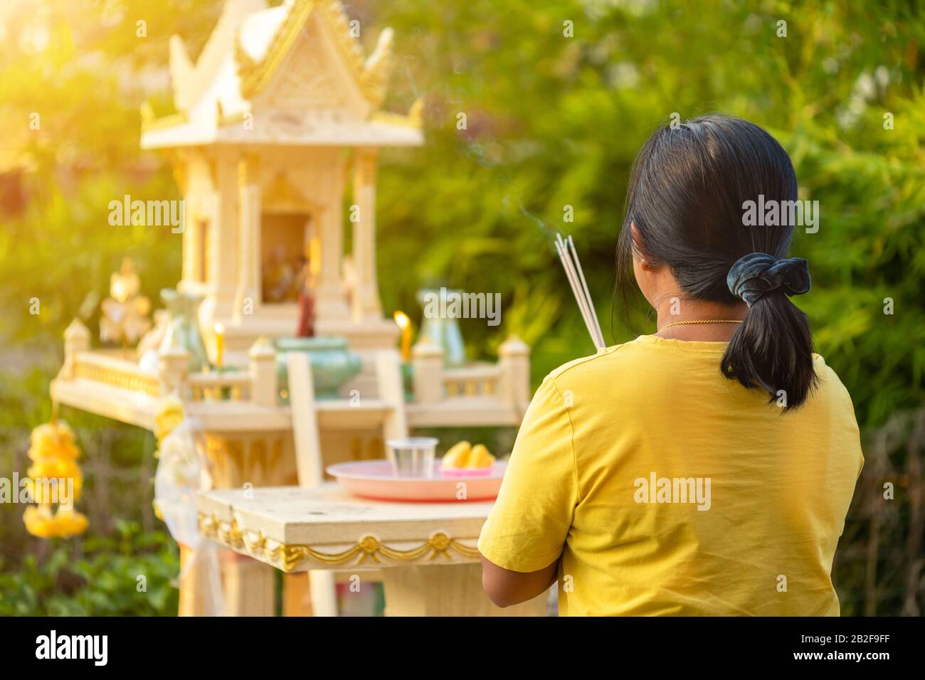 Rückseite der thailändischen Frau, die vor dem Joss House steht und mit Weihrauch betet. Traditionelles thailändisches Kulturkonzept Stockfoto