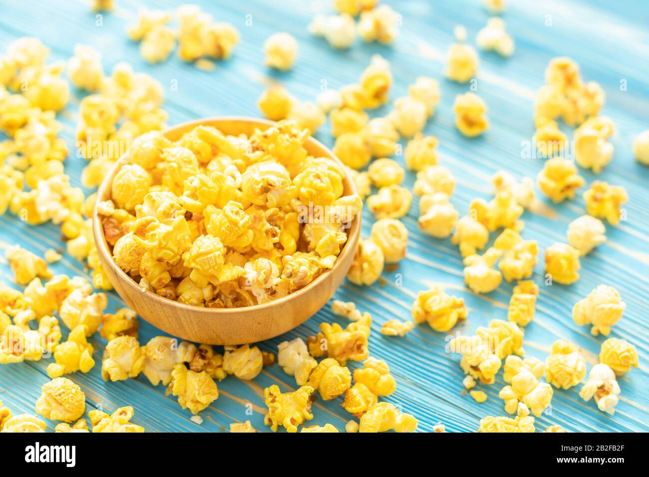 Von oben gelbes Popcorn auf blauem Holzbohlenhintergrund. Food- oder Snack-Konzept Stockfoto