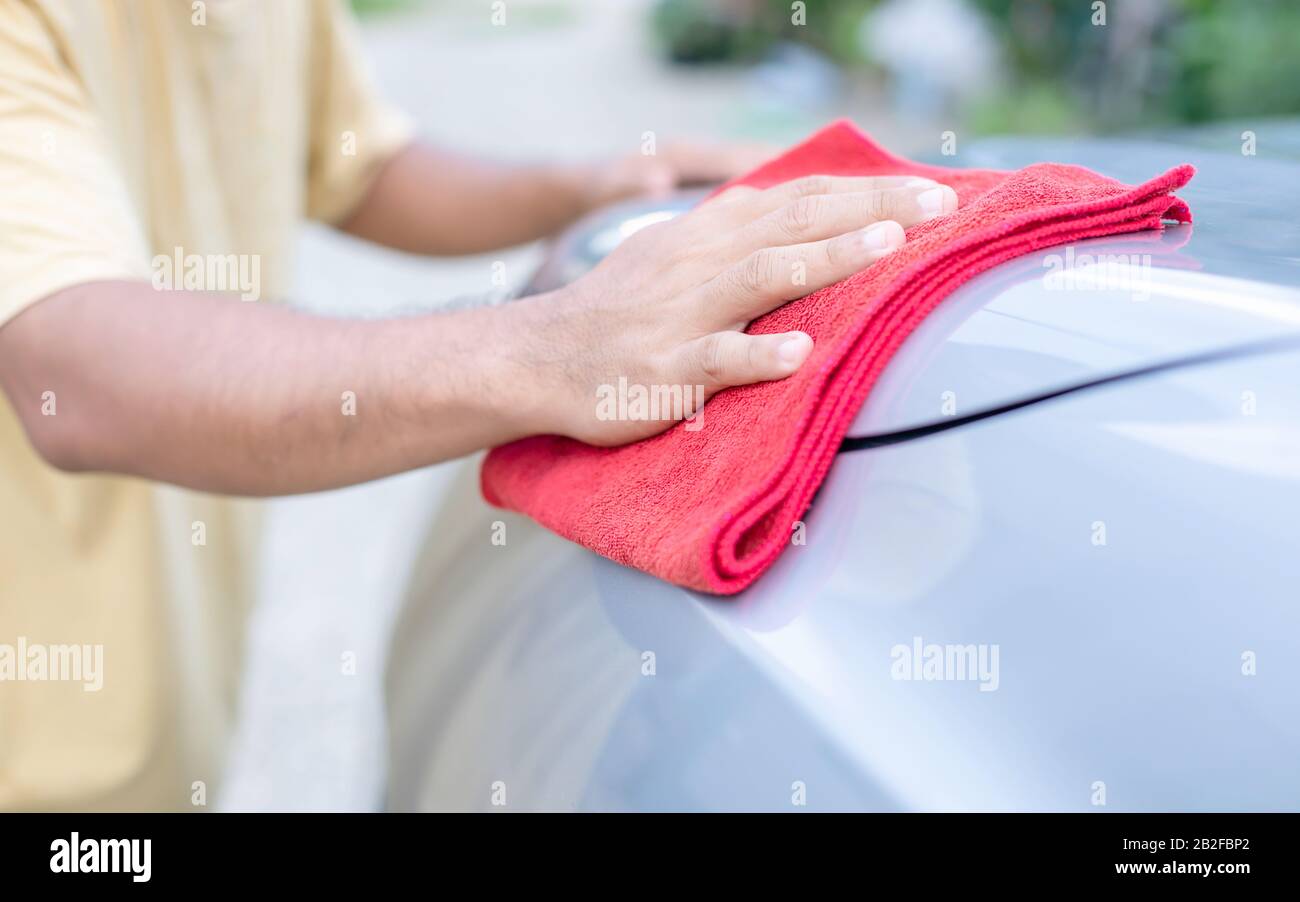 Die Hand der Menschen, die mit rotem Tuch den Körper des SUV-Autos reinigen. Reinigung oder Waschen von Autos Stockfoto