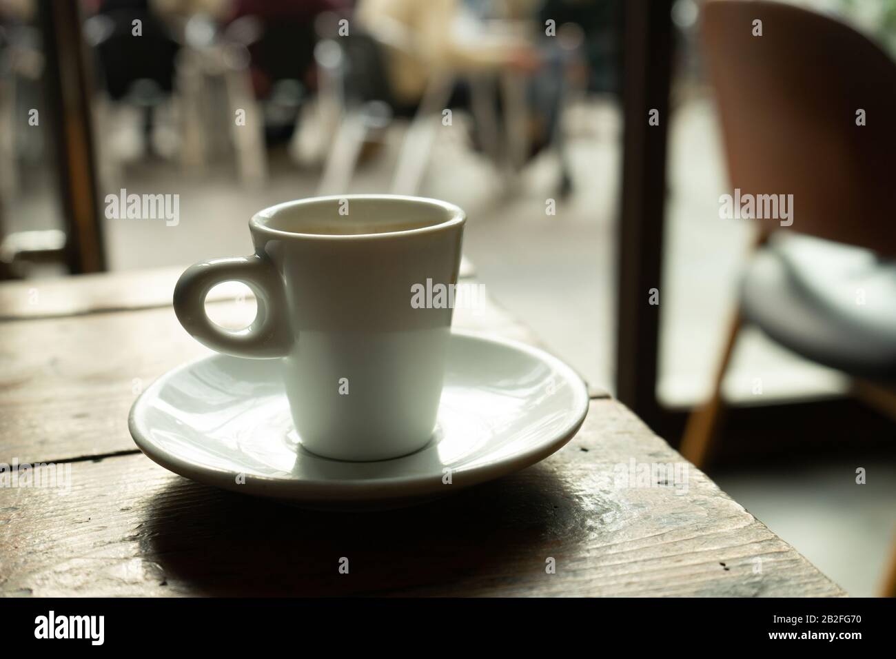 Tasse Kaffee in einem schönen Hipster-Café. Weich fokussiertes Bild. Tasse Espresso auf dem alten Tisch der Cafeteria. Stockfoto