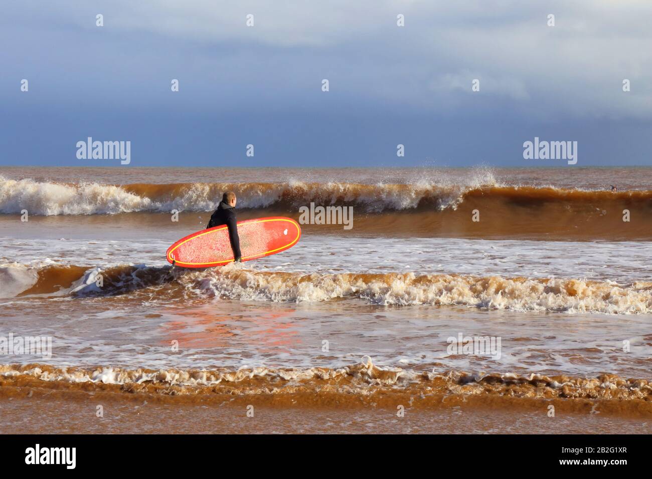 Surfer in Wetsuit mit Surfbrett am Strand in Sidmouth, Devon Stockfoto