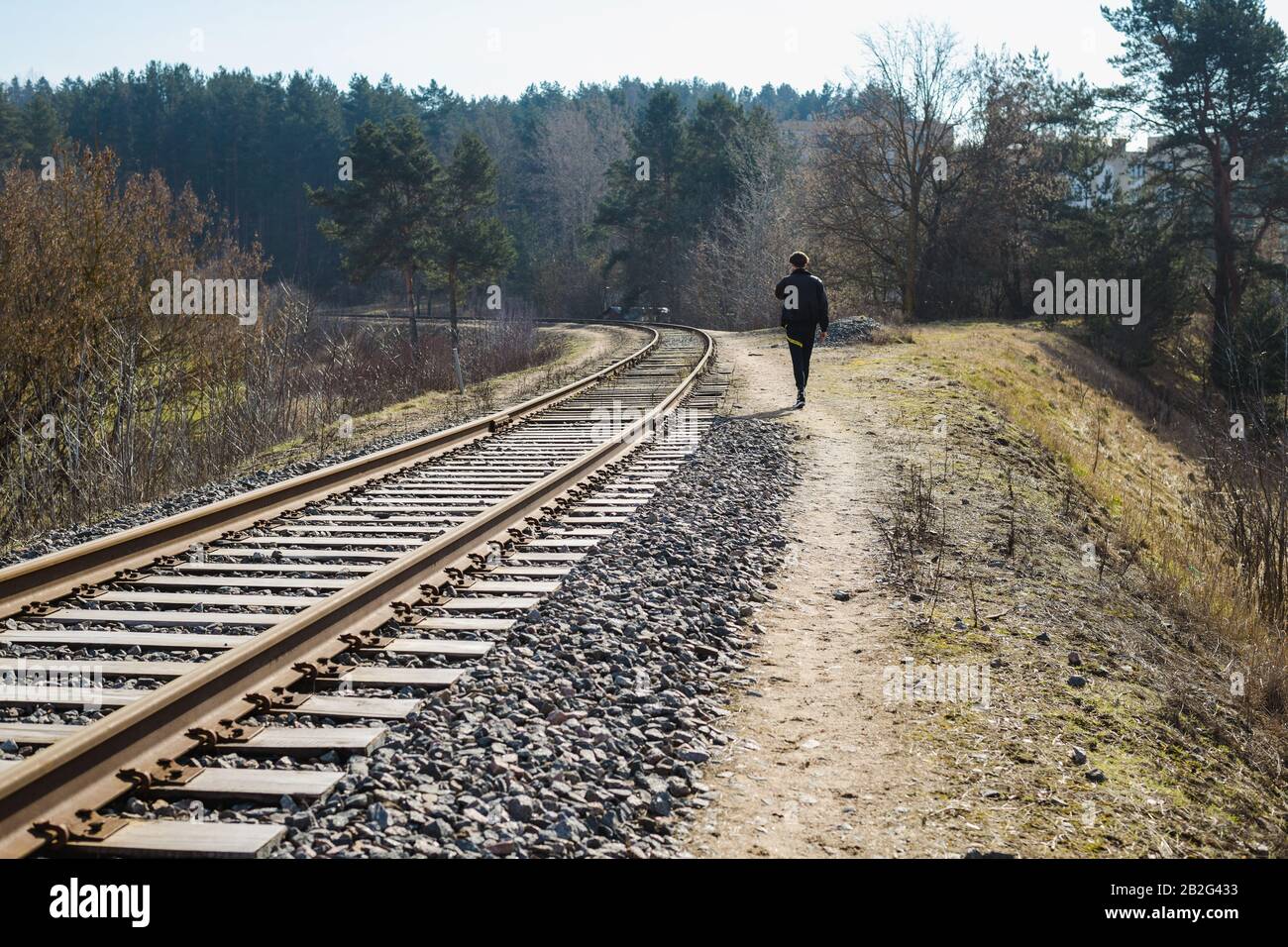 Ein schwarz gekleideter Mann, der allein auf nahe gelegenen Bahngleisen unterwegs ist Stockfoto