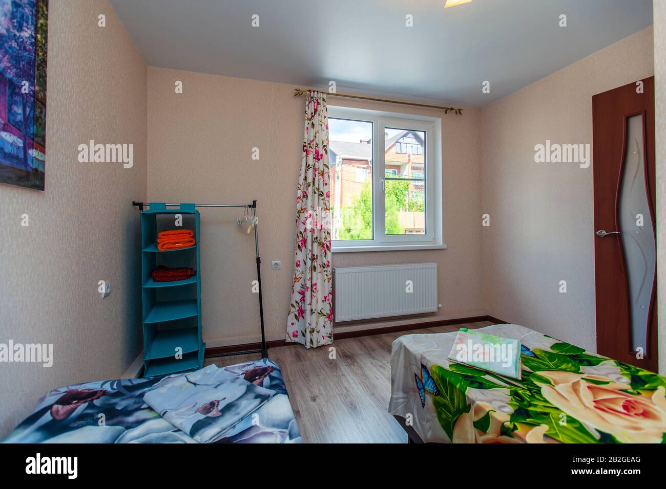 Ein kleines Zimmer in der Pension mit zwei Einzelbetten mit grüner und blauer Bettdecke. Stockfoto