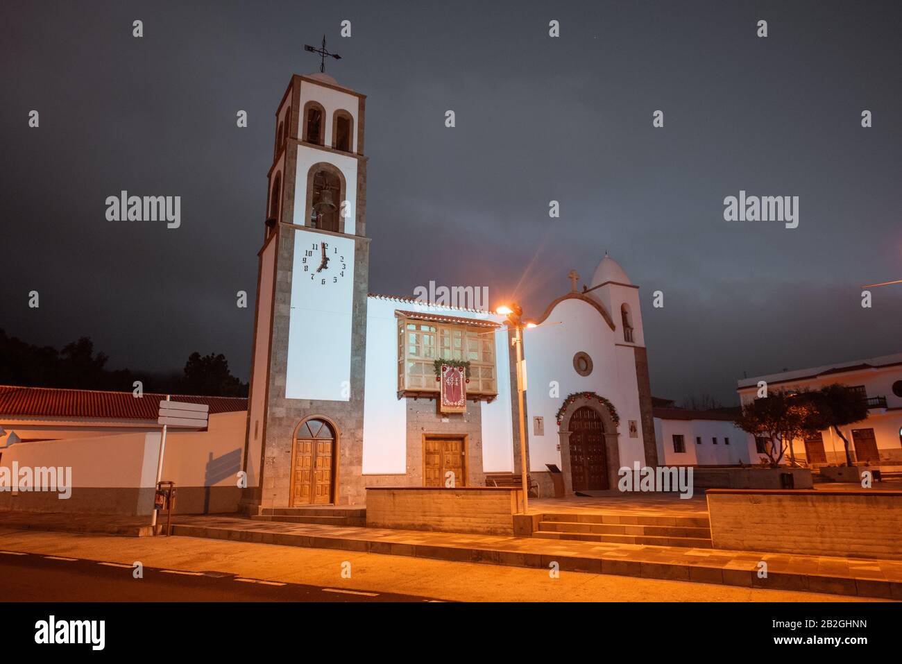 Nachtblick auf den zentralen Platz mit alter Kirche im Dorf Santiago del Teide im Nordwesten der Insel Tenera, Spanien Stockfoto