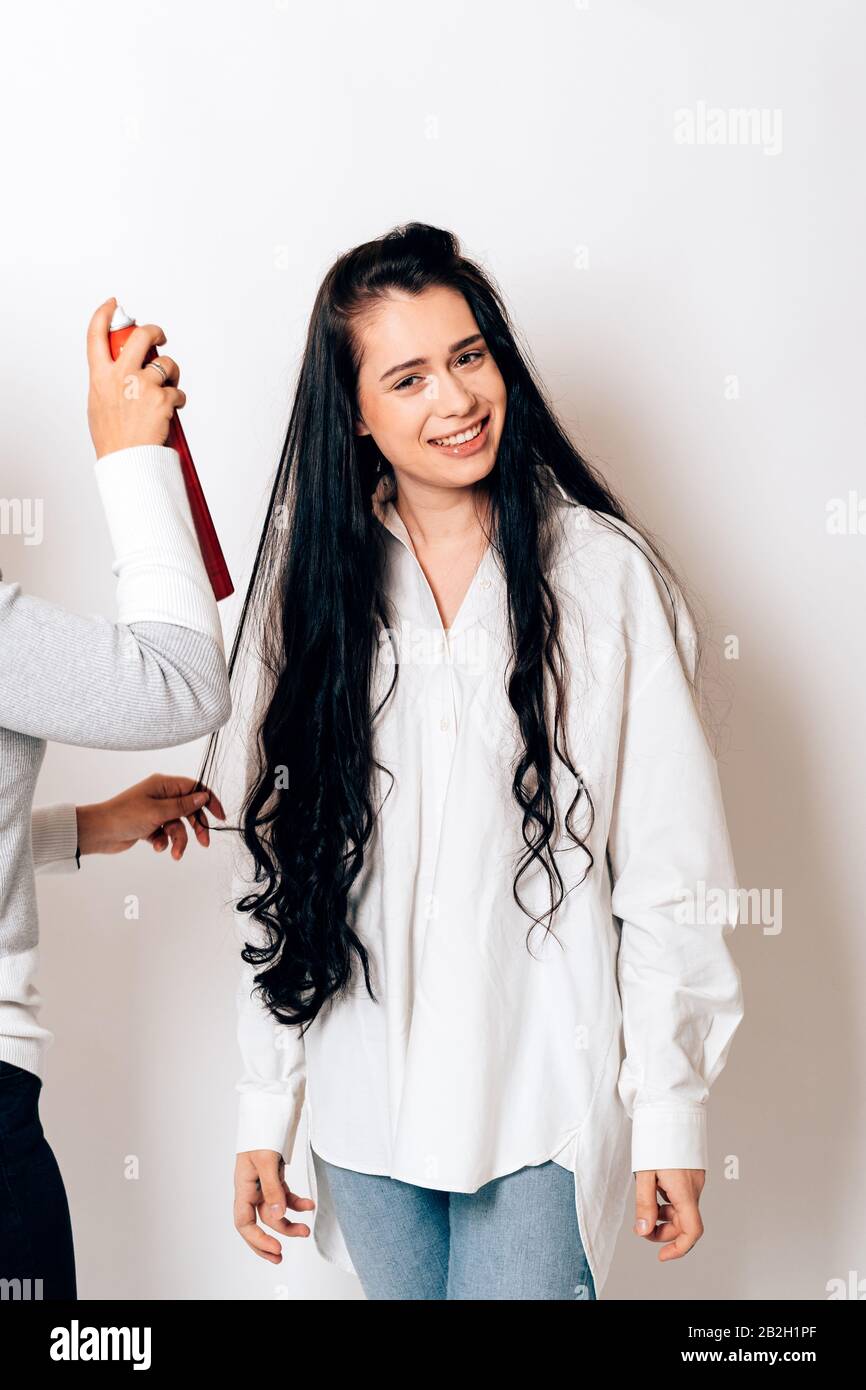 Ein lächelndes Modell bekommt ihr Haar von der Make-up-Künstlerin gemacht Stockfoto