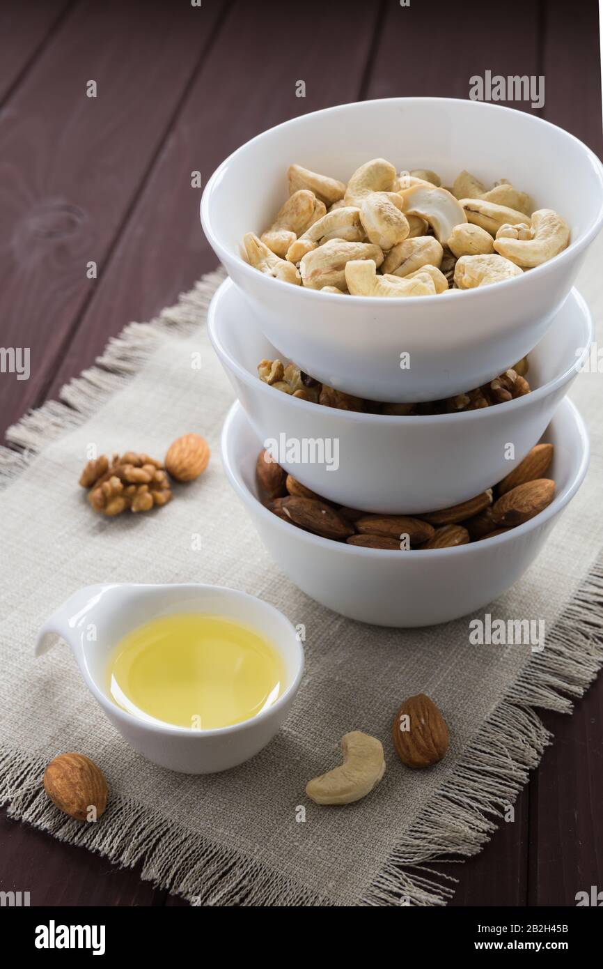 Ernährungskonzept, Mandeln, Walnüsse und Cashewnüsse mit Öl auf einem Holztisch Stockfoto