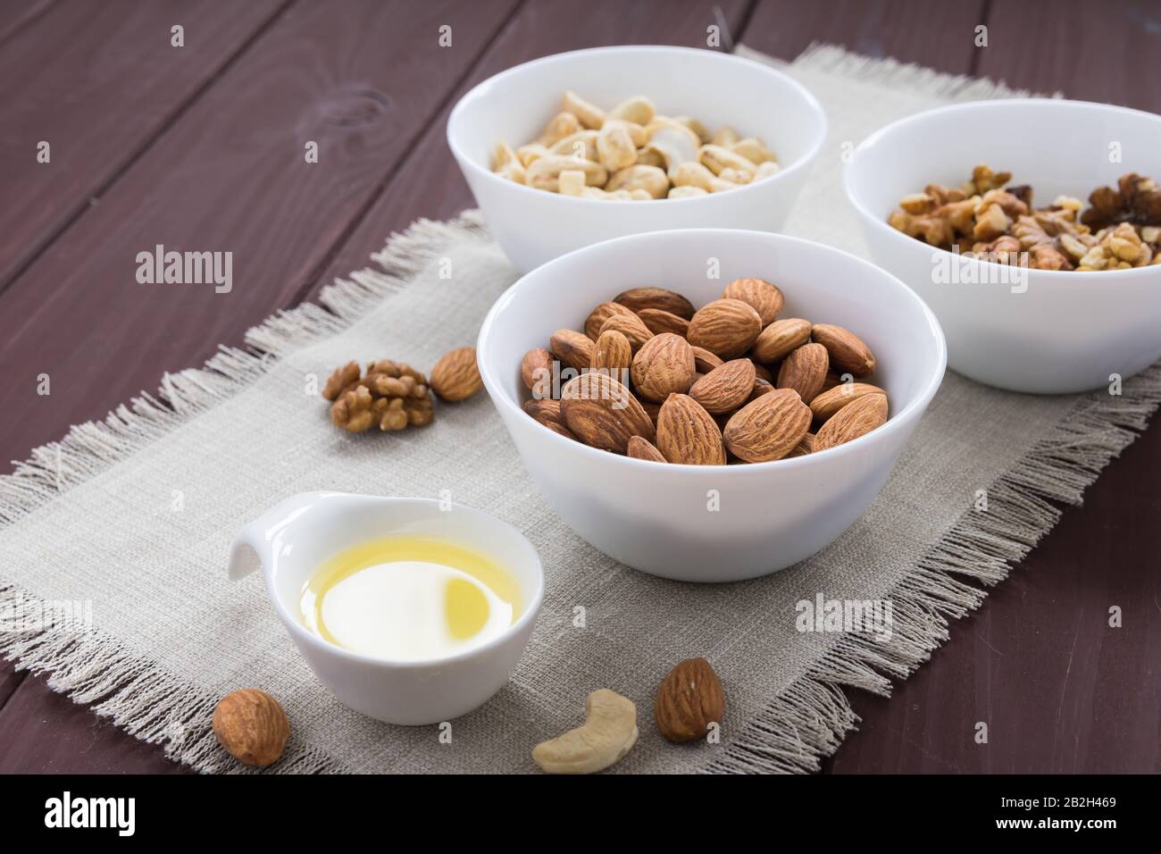 Ernährungskonzept, Mandeln, Walnüsse und Cashewnüsse mit Öl auf einem Holztisch Stockfoto