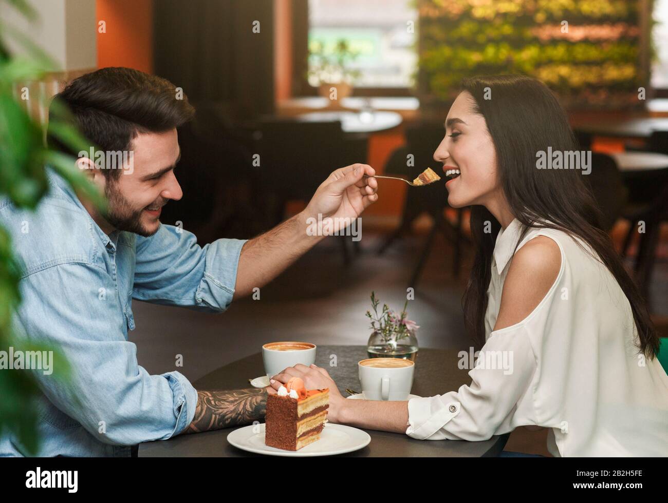 Liebevoller Freund, Der Freundin Schmeckt Kuchen In Der Cafeteria Stockfoto