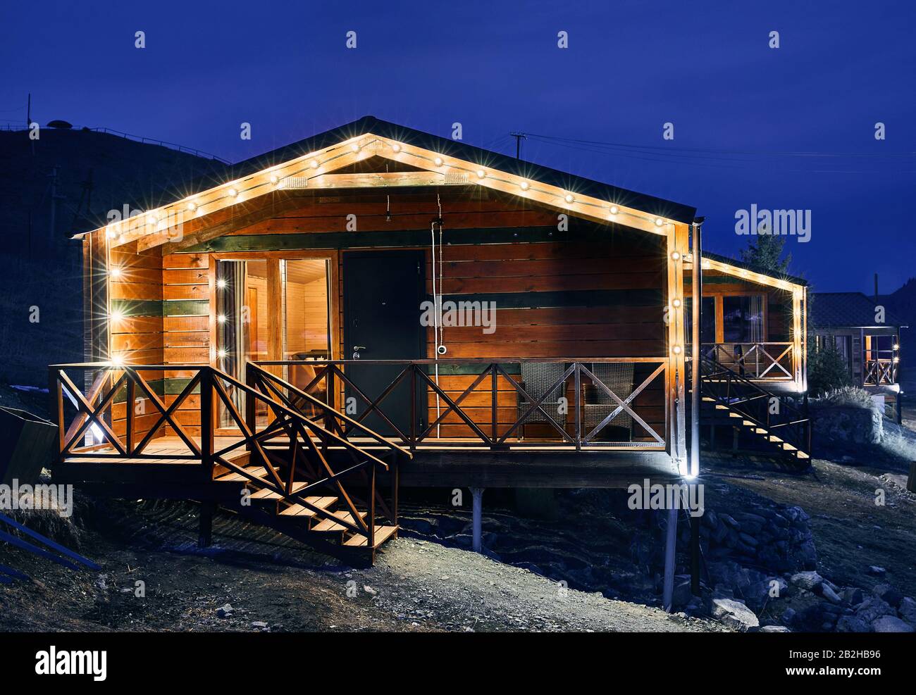 Modernes Holzhaus mit gelben Glühbirnen im Bergresort Stockfoto