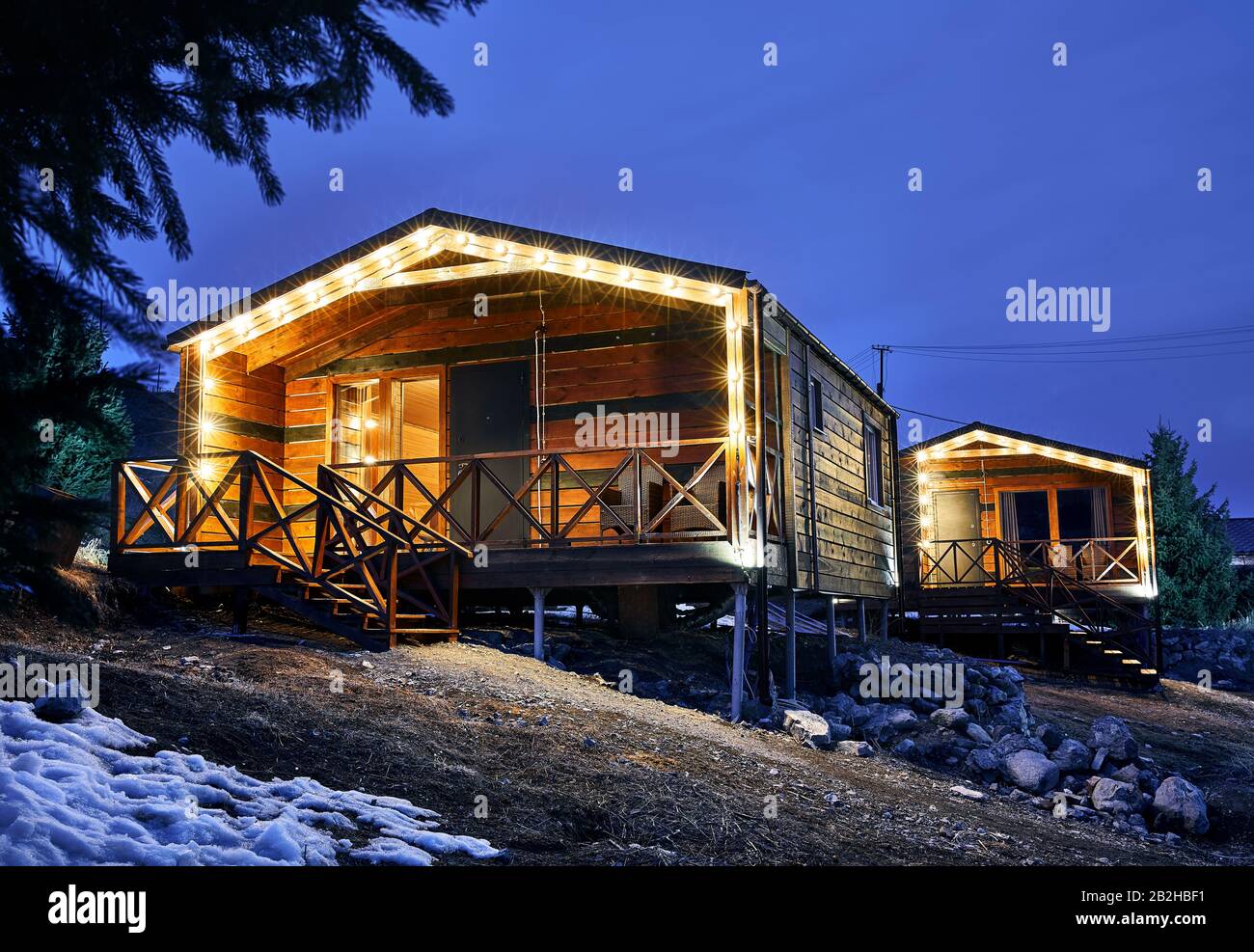 Moderne Holzhäuser mit gelben Glühbirnen im Bergresort Stockfoto