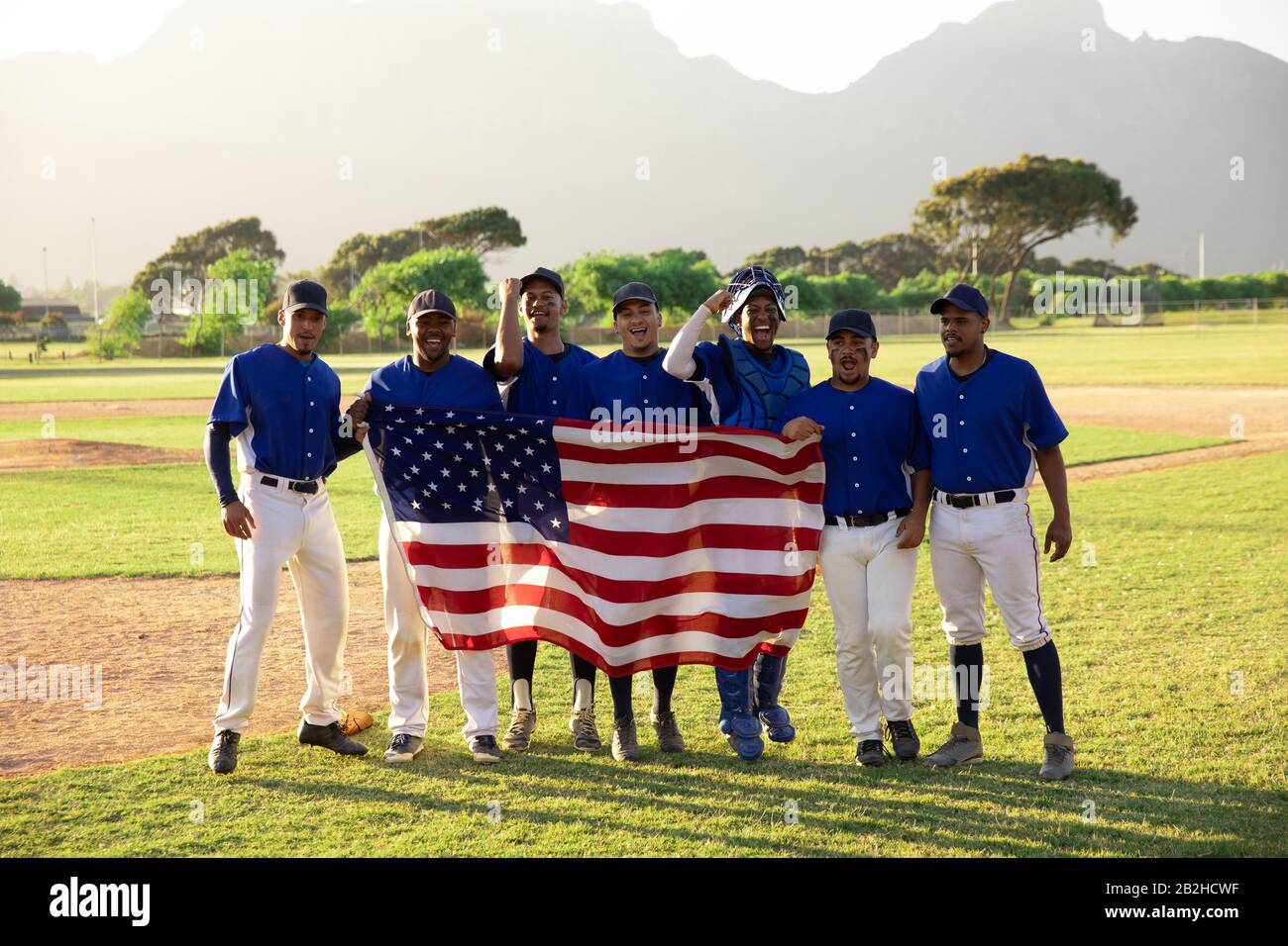 Baseballspieler, die mit einer amerikanischen Flagge auf Linie stehen Stockfoto