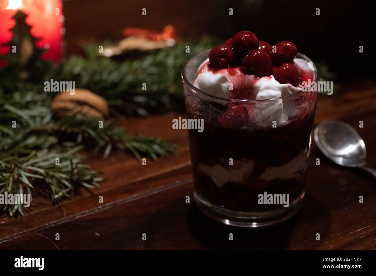 Ein veganes Dessert mit Schokolade, Sahne und Kirschen auf einem Tisch mit Weihnachtsdekoration Stockfoto