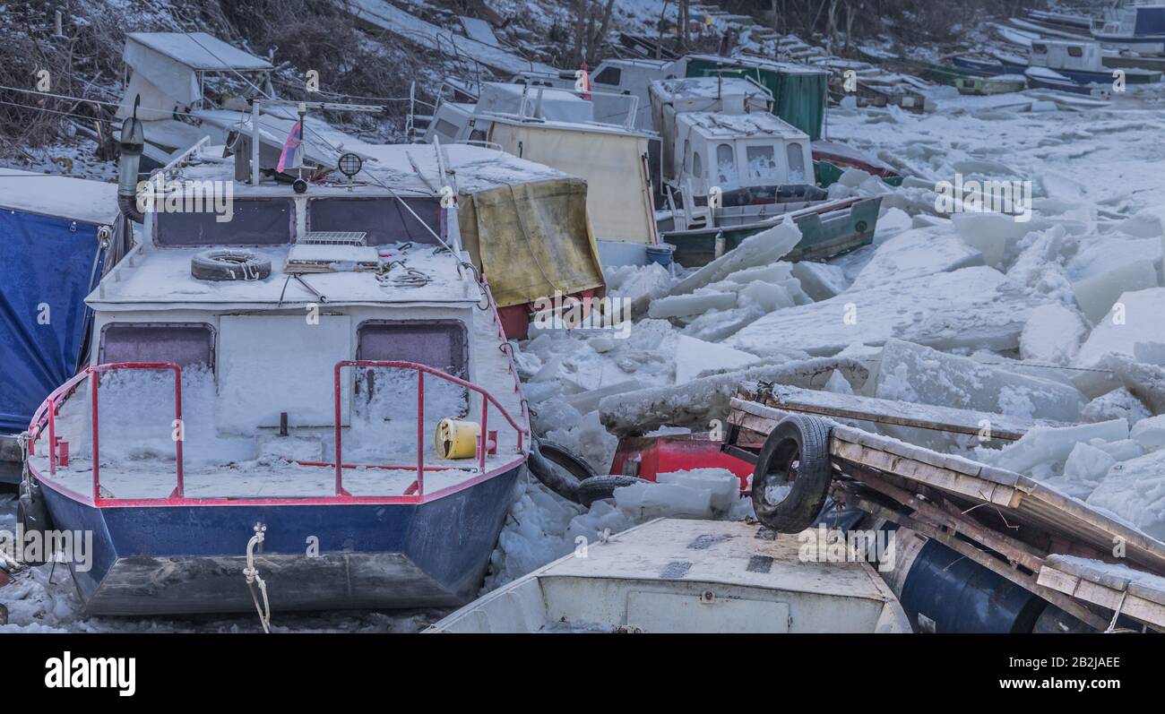 Viele zerstörte Boote an einem gefrorenen Donau-Fluss mit vielen Eiswürfeln in der Nähe von Belgrad, Zemun, Serbien Stockfoto