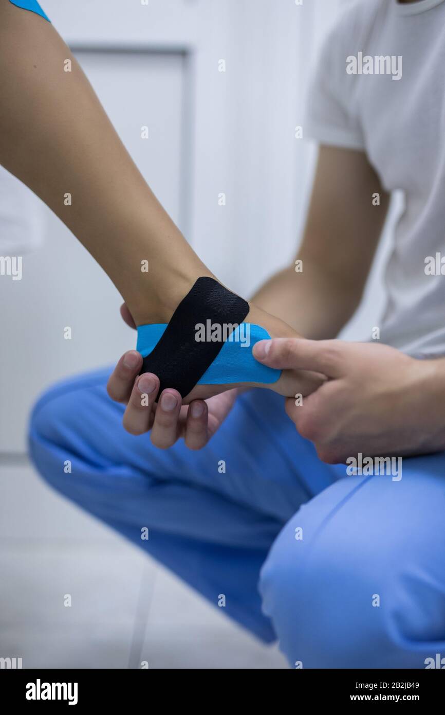 Ein Physiotherapeut ist Kinesio Tape auf Bein des Patienten anwenden. Stockfoto