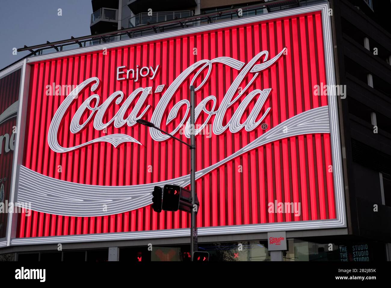 Kings Cross Coke Schild in der Nähe, kurz nachdem sie 2016 ersetzt wurde, leuchtet und beleuchtet in knackigem Abendlicht, Straßenszene mit Verkehr, Dämmerung Stockfoto