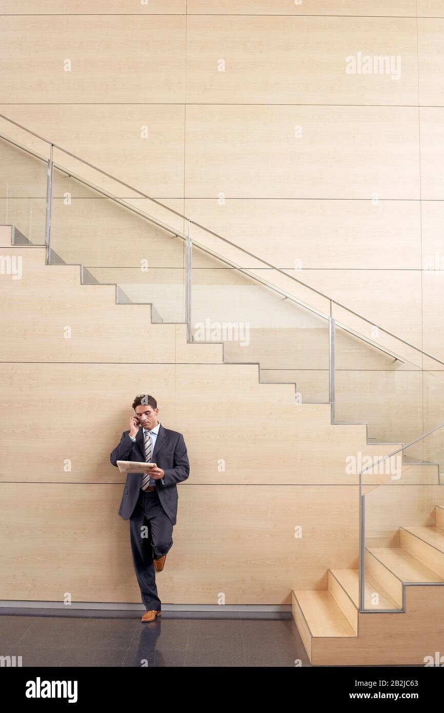 Geschäftsmann auf Handy unten im Treppenhaus Stockfoto