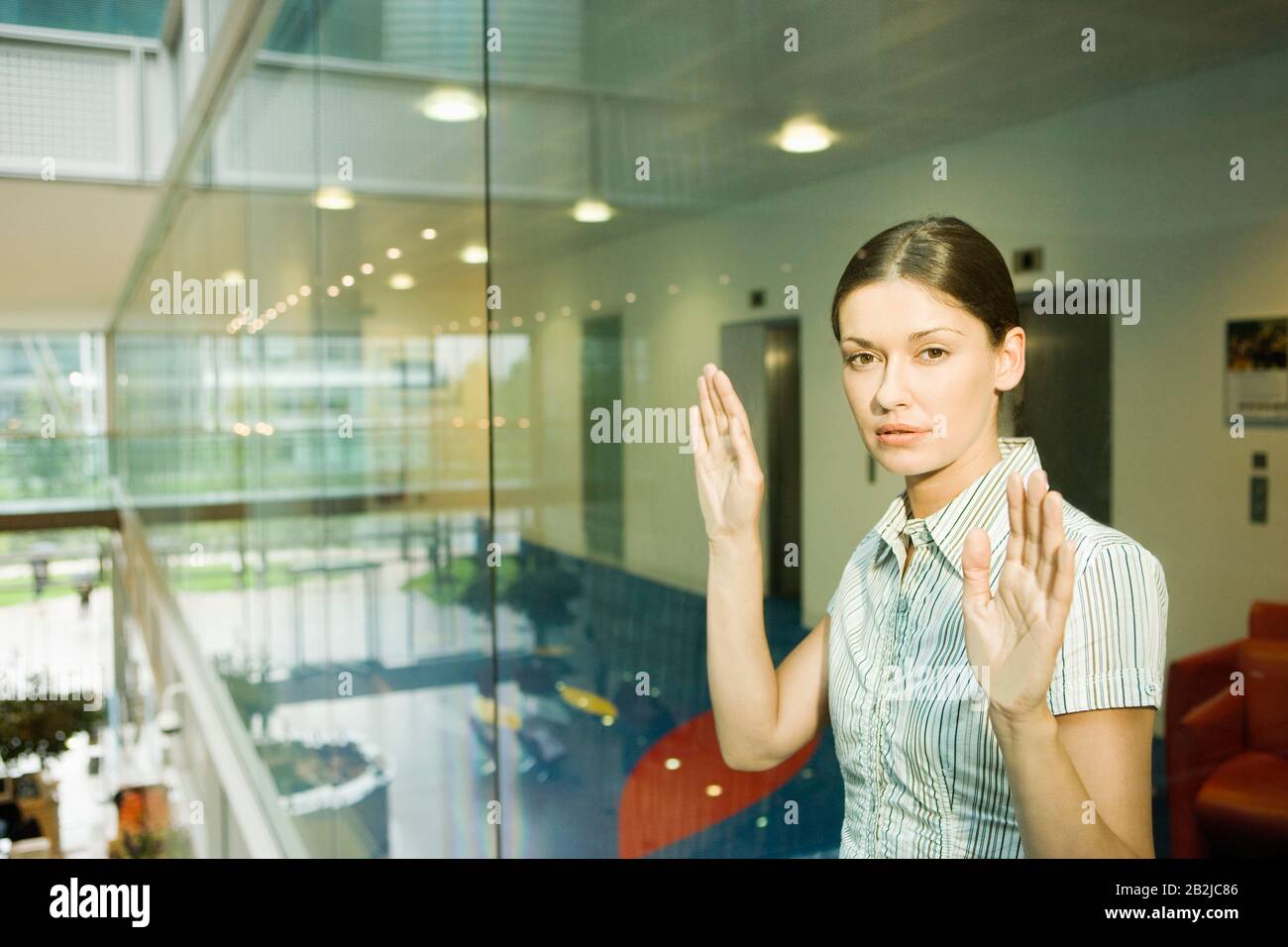 Frau Hinter Glaswand im Büroporträt Stockfoto