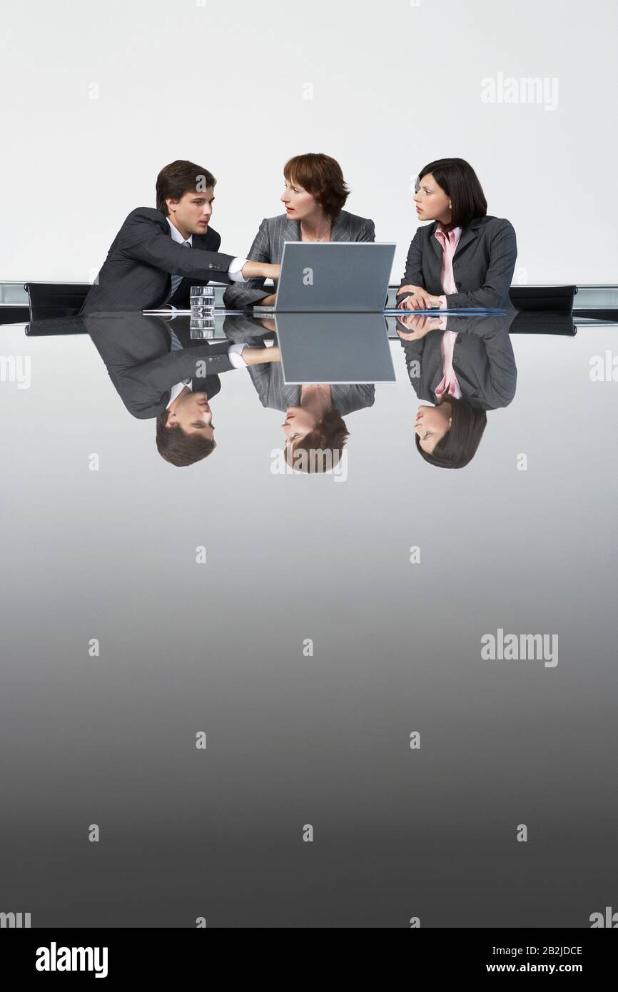 Drei Geschäftskollegen verwenden Laptop am Konferenztisch Stockfoto