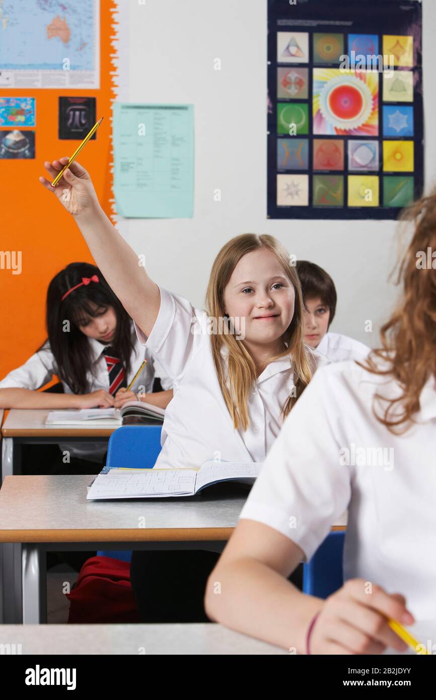 Mädchen (10-12) mit Down-Syndrom, das die Hand im Klassenzimmer erhöht Stockfoto
