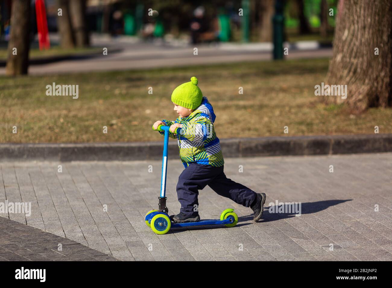 Süßer kleiner Junge, der einen Kickroller reitet. Gesunde Outdoor-Aktivität Stockfoto