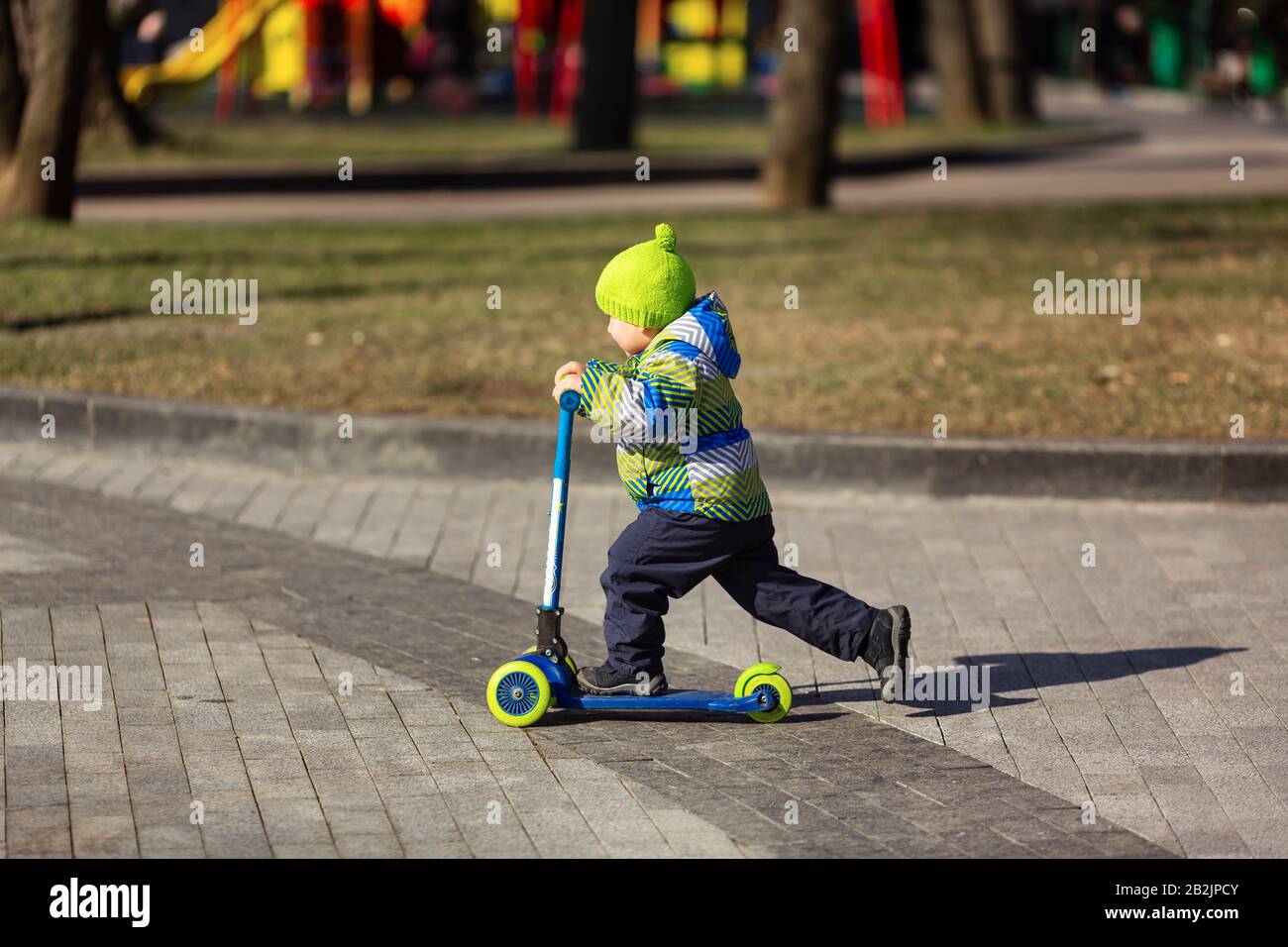 Süßer kleiner Junge, der einen Kickroller reitet. Gesunde Outdoor-Aktivität Stockfoto