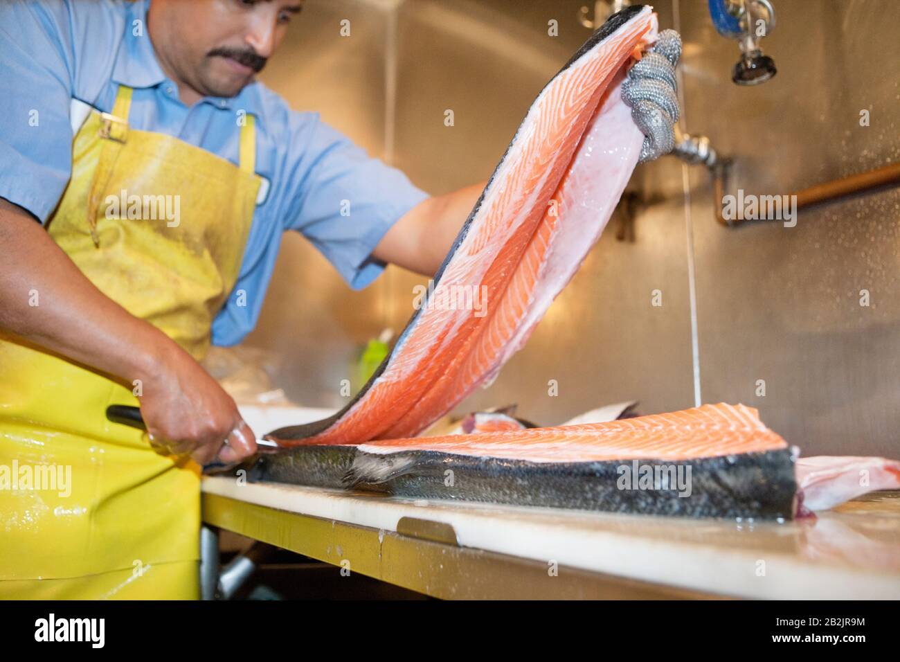 Reifer Fischhändler, der Lachsfische auf dem Tisch schaufelt Stockfoto