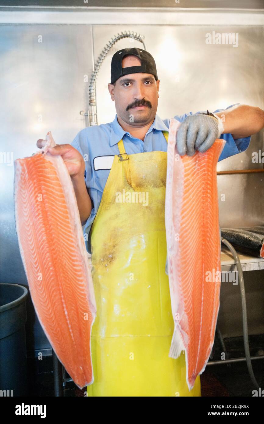 Portrait von reifen Fischhändlern, die in Scheiben geschnittenen Lachs halten Stockfoto