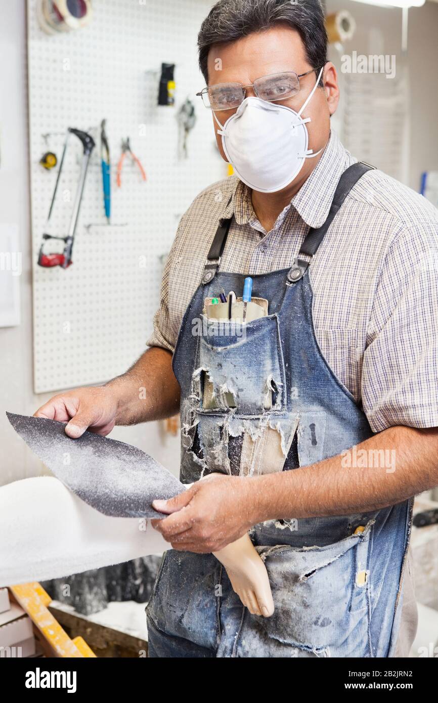 Porträt eines reifen männlichen Arbeiternehmers, der prothetische Extremitäten in der Werkstatt poliert Stockfoto