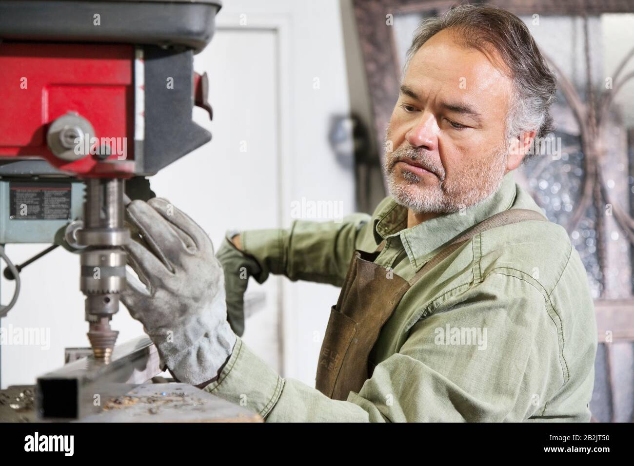 Ausgereifter Metallarbeiter, der in der Werkstatt mit Maschinen arbeitet Stockfoto
