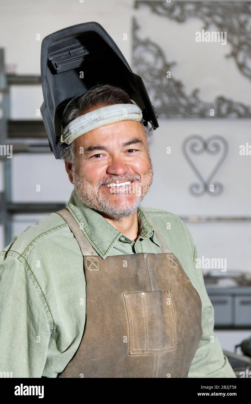 Porträt eines glücklichen, reifen Mannes, der in der Werkstatt Schweißmaske trägt Stockfoto