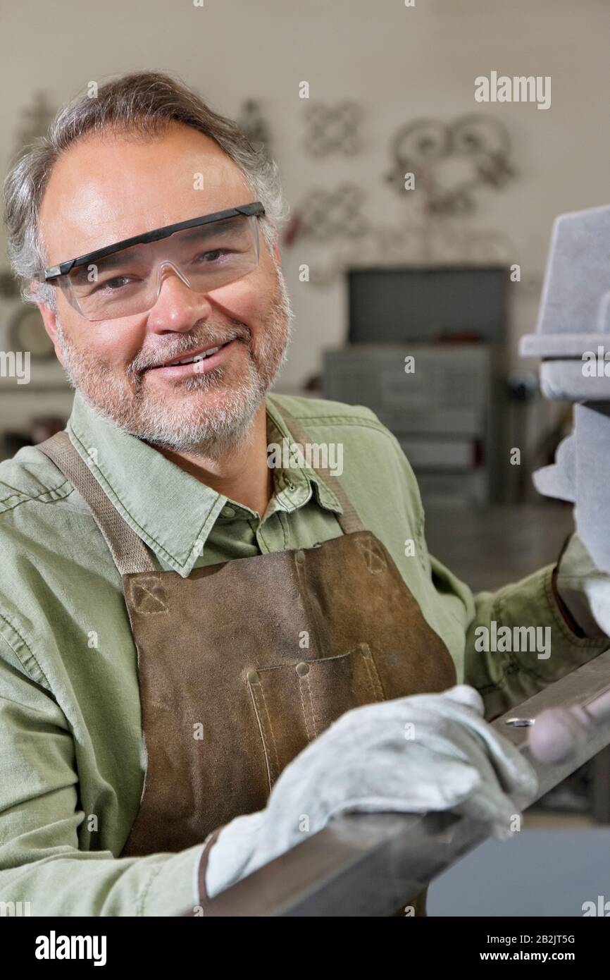 Portrait von glücklichen, reifen Metallarbeitern, die in der Werkstatt Schutzbrillen tragen Stockfoto