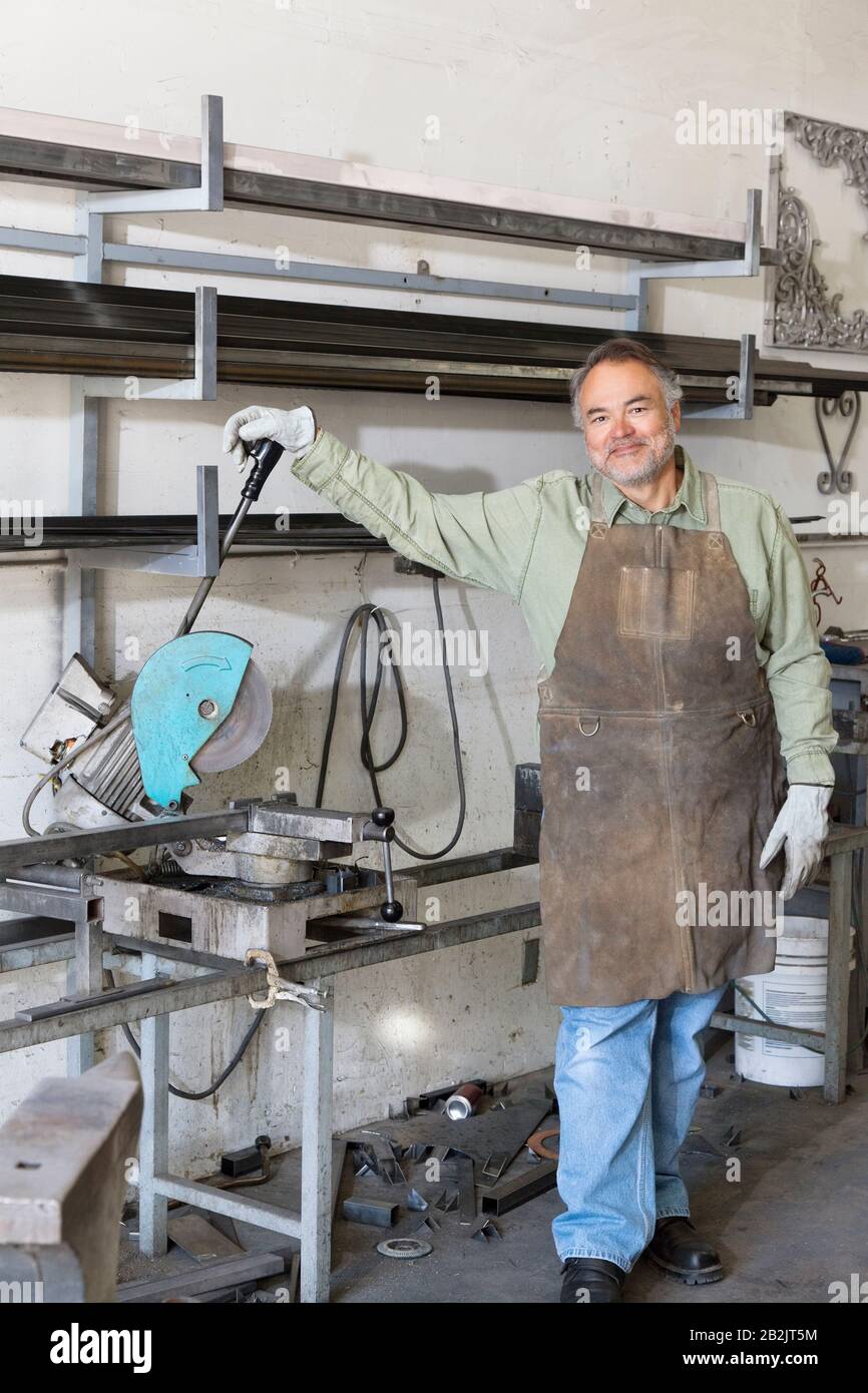 Porträt eines reifen Mannes, der in der Werkstatt an der elektrischen Säge steht Stockfoto