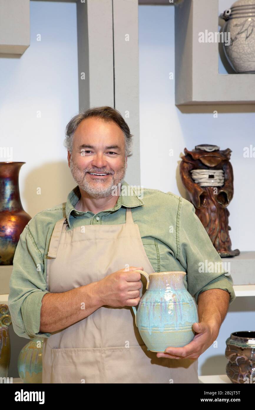 Porträt eines glücklichen Töpfers, der einen Keramiktopf im Atelier des Künstlers hält Stockfoto