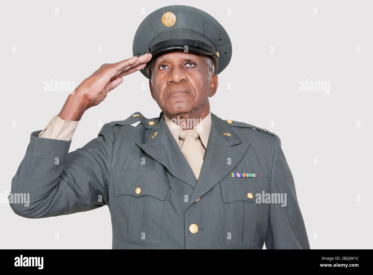 Hoher männlicher US-Militäroffizier, der über grauem Hintergrund saluiert Stockfoto