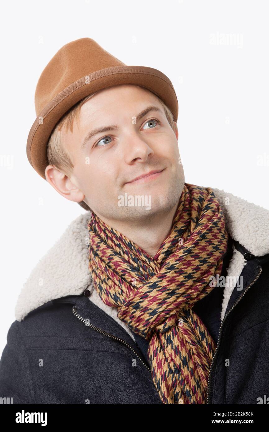Fröhlicher junger kaukasischer Mann in warmer Kleidung, der vor weißem Hintergrund wegschaut Stockfoto