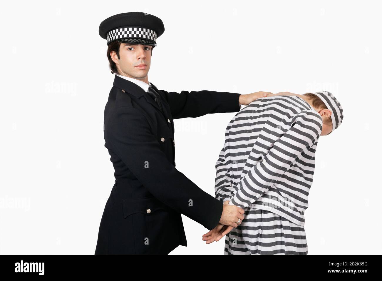 Porträt eines selbstbewussten Polizisten mit männlichem Häftling vor weißem Hintergrund Stockfoto