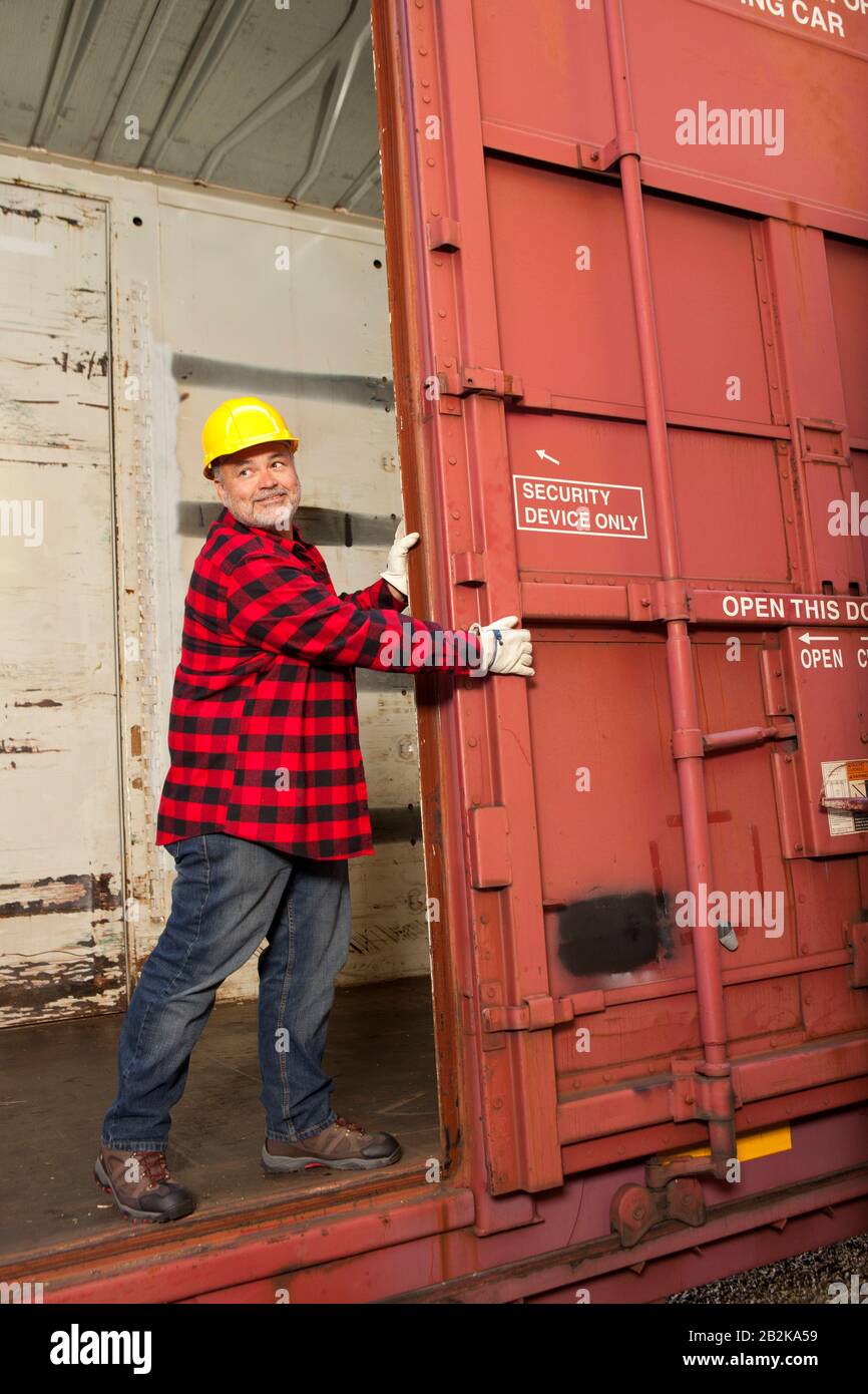 Arbeiter mittleren Alters öffnen die Tür des Metalleisenbahnwagens Stockfoto