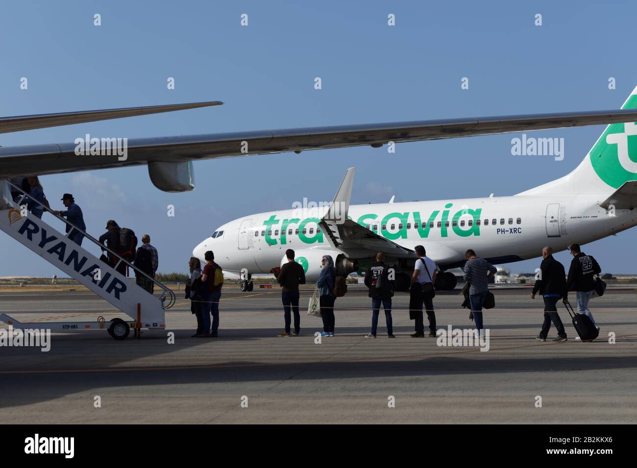 Passagiere, die mit dem Ryanair-Flugzeug gegen das Flugzeug einer anderen Billigfluggesellschaft Transavia im Flughafen Faro, Portugal, einsteigen Stockfoto