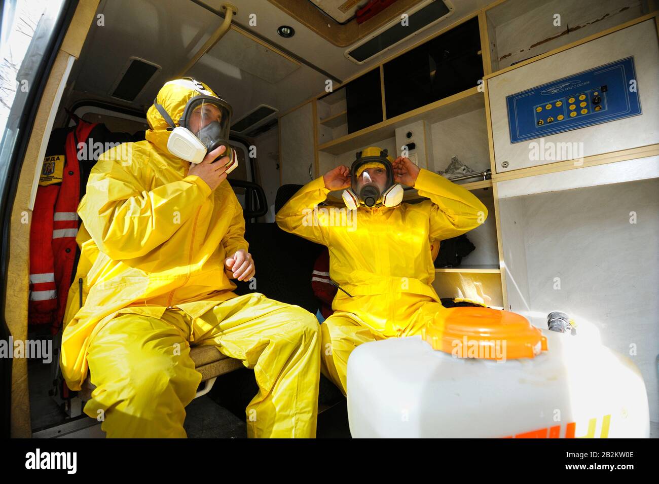 Sanitäter sitzen im Rettungswagen und tragen gelbe Schutzkleidung und Masken zur Desinfektion von Coronavirus, Training. Februar 202 Stockfoto