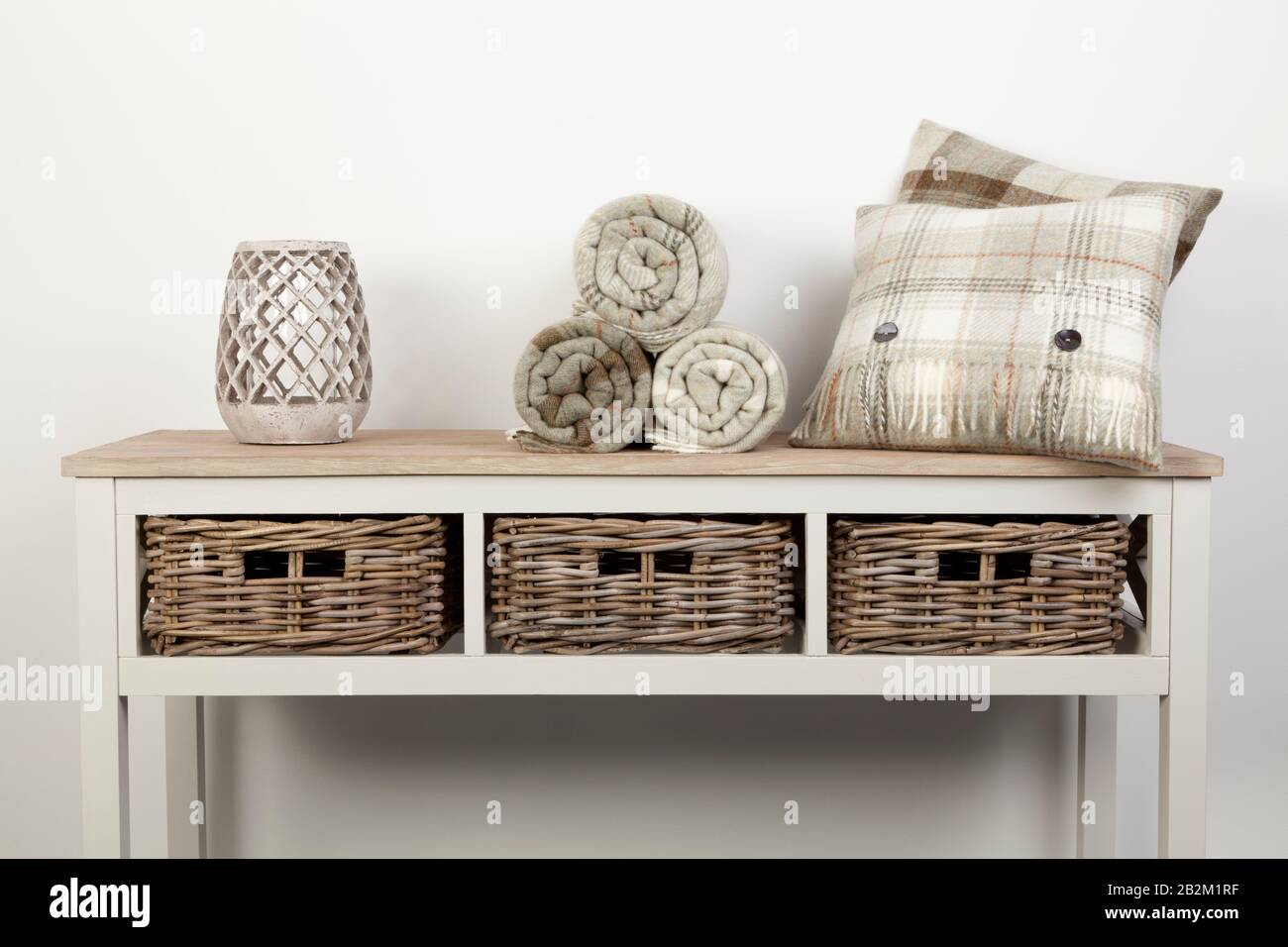 Weißer Holztisch im Sideboardstil mit natürlichen Kissen, Würfen und Verzierungen und Korbkörben auf weißem Hintergrund Stockfoto