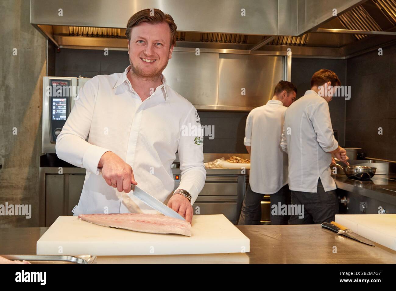 Hamburg, Deutschland. März 2020. Kevin Fehling (l), Spitzenkoch, steht in seinem Restaurant The Table Kevin Fehling und schneidet ein Fischfilet. Restaurantführer Michelin Deutschland hat die Stars der besten Restaurants angekündigt. Mit dem Zustandekommen von Berlin verfügen Deutschlands drei größten Städte erstmals über ein Drei-Sterne-Restaurant. In Hamburg konnte "Der Tabellenerste Kevin Fehling" den Spitzenpreis halten. Kredit: Georg Wendt / dpa / Alamy Live News Stockfoto