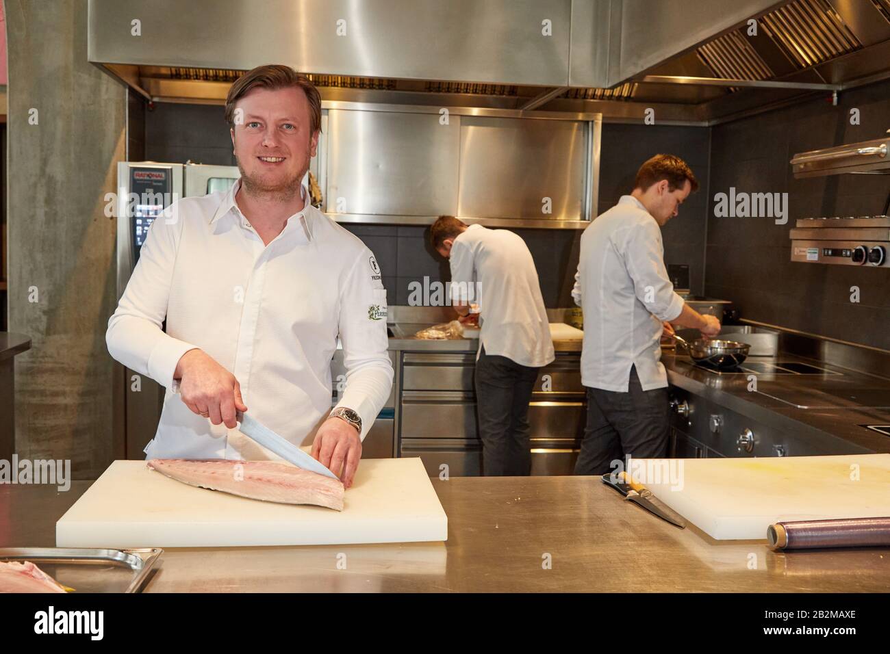Hamburg, Deutschland. März 2020. Kevin Fehling (l), Spitzenkoch, steht in seinem Restaurant The Table Kevin Fehling und schneidet ein Fischfilet. Restaurantführer Michelin Deutschland hat die Stars der besten Restaurants angekündigt. Mit dem Zustandekommen von Berlin verfügen Deutschlands drei größten Städte erstmals über ein Drei-Sterne-Restaurant. In Hamburg konnte "Der Tabellenerste Kevin Fehling" den Spitzenpreis halten. Kredit: Georg Wendt / dpa / Alamy Live News Stockfoto