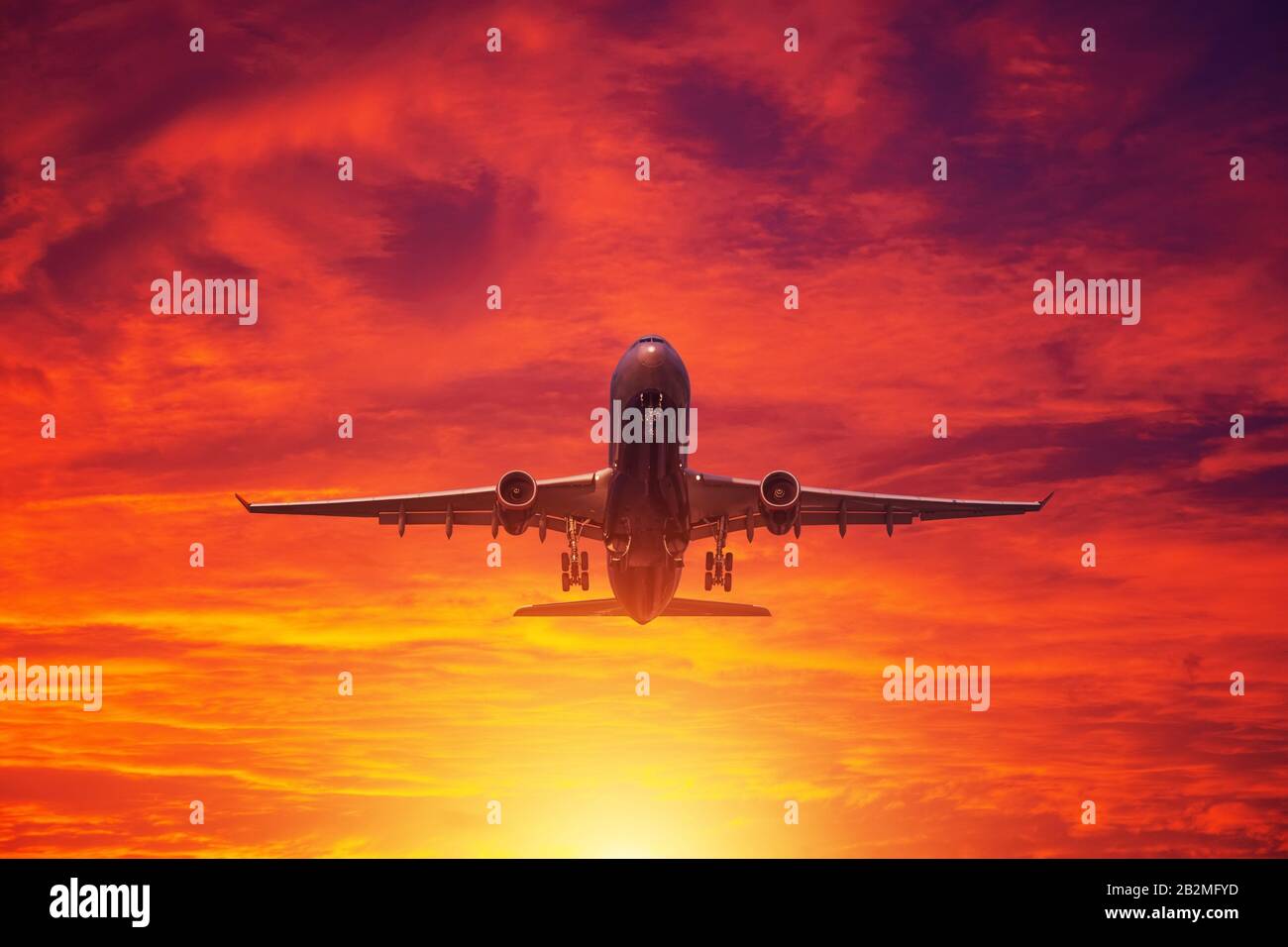 Das Flugzeug geht auf dem Hintergrund von Wolken am Abend und einem engen roten Sonnenuntergang vom Flughafen aus Stockfoto