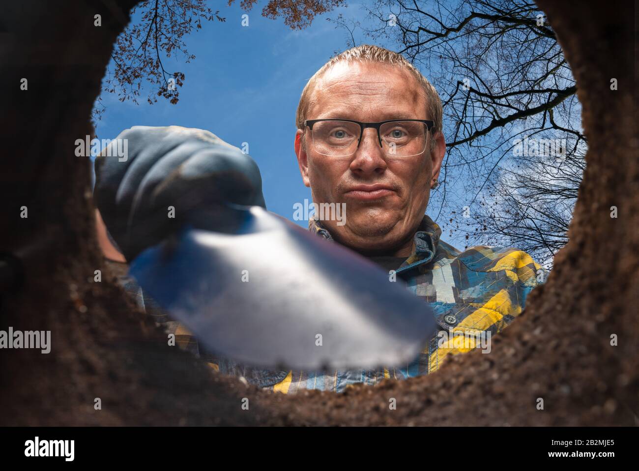 Ein Mann mit einer Schaufel gräbt eine untere Ansicht des Lochs Stockfoto