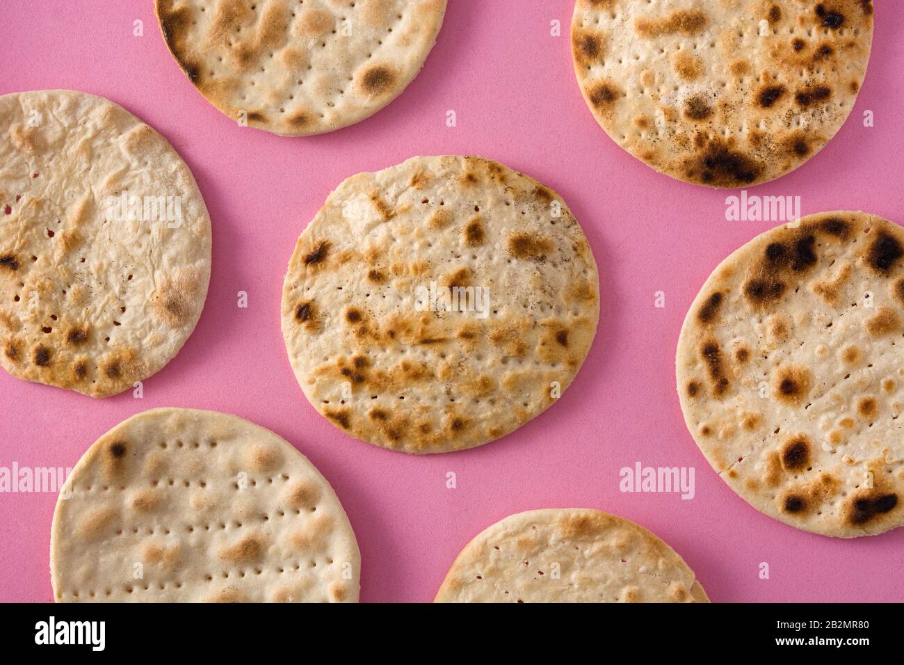 Handgemachtes Matzah für das jüdische Passah auf pinkfarbenem Hintergrund Stockfoto