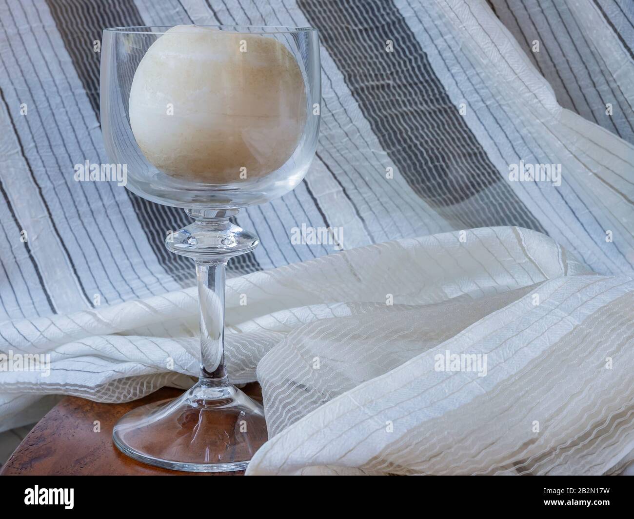 Schöne Inneneinrichtung mit Glaskerze auf Holztisch und Vorhang Stockfoto
