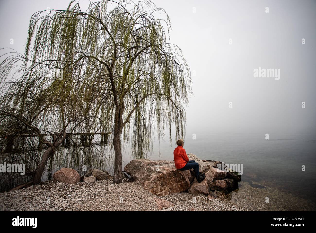 Orangefarbene Jacke am Gardasee, Italien Stockfoto
