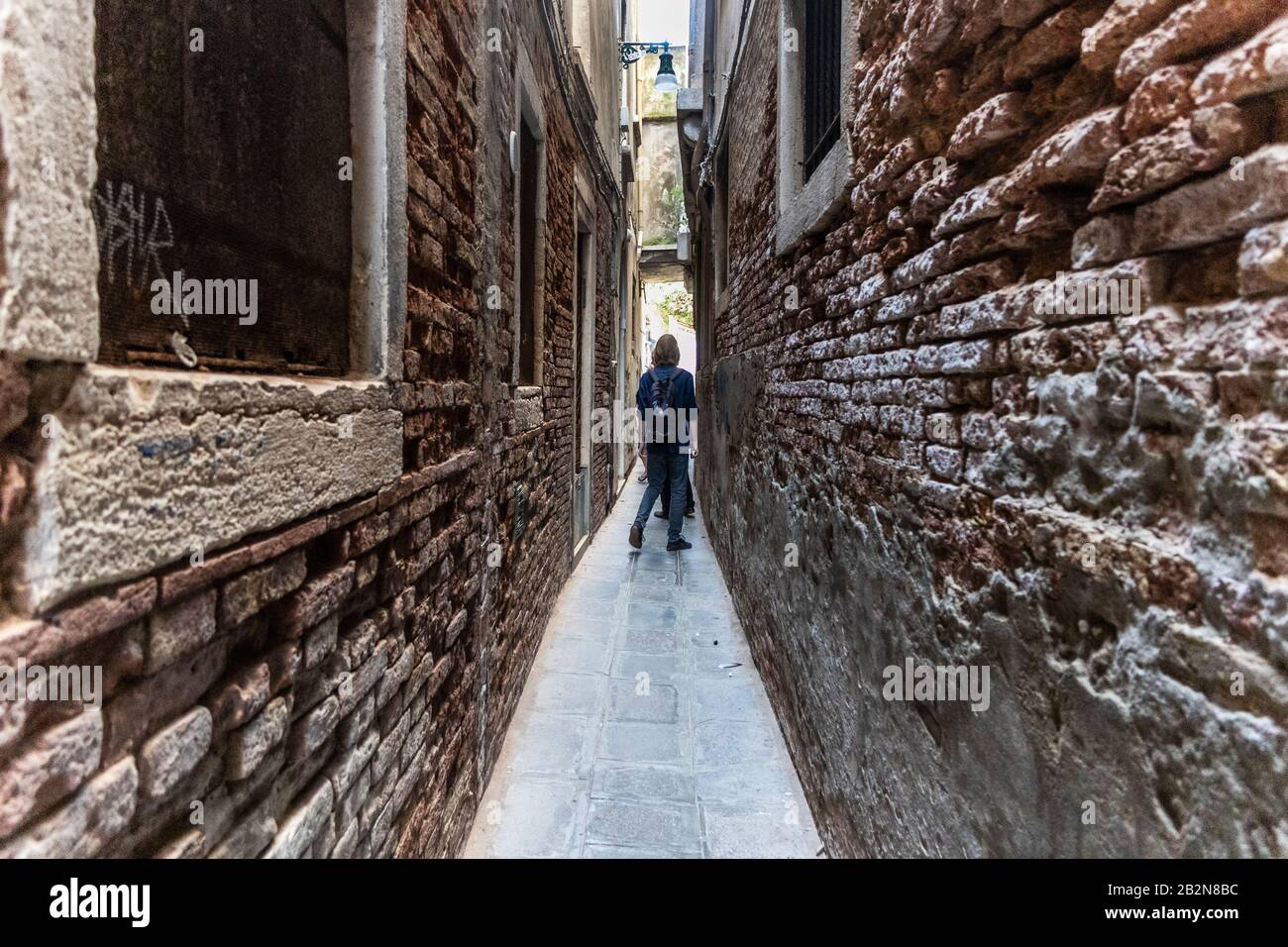 Person, die einen Schmalen Gasse in Venedig entlang spazieren geht. Italien Stockfoto