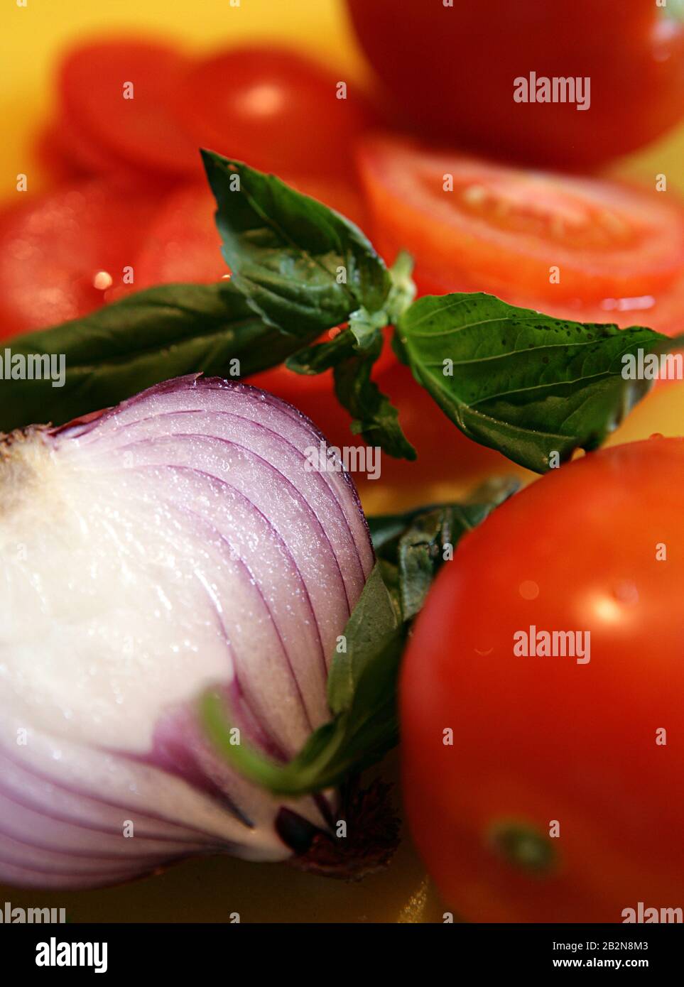 Halbe Zwiebel, Tomate und geschnittene Tomaten- und Basilikumsalatplatte Stockfoto
